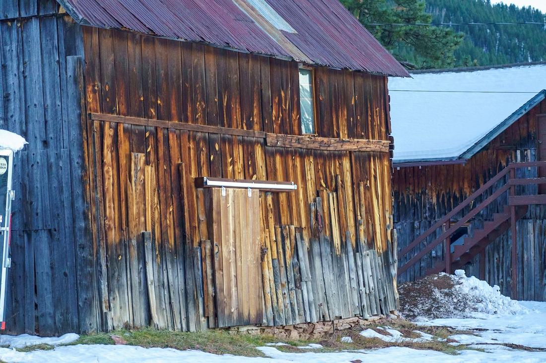 Weathered wooden barn beside snow