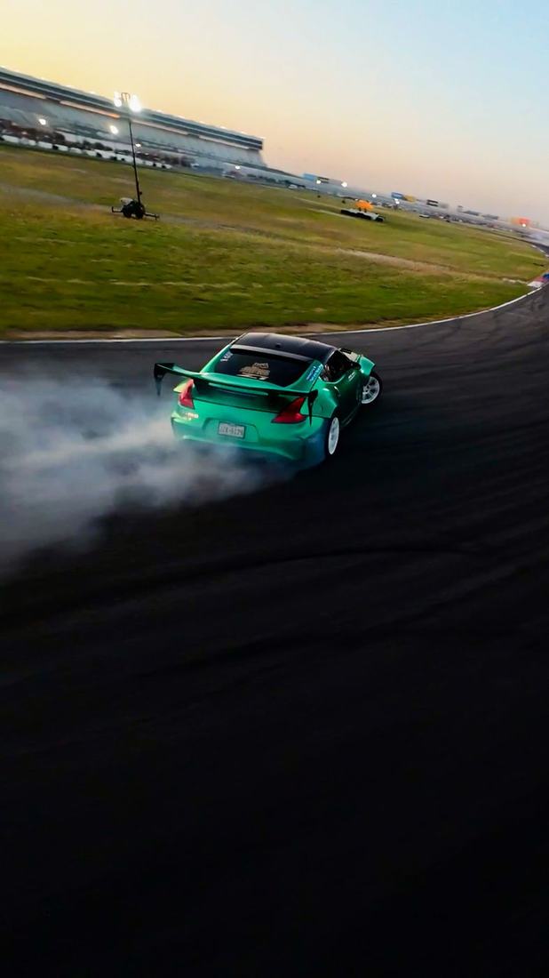 Green drift car sliding through a corner in tire smoke