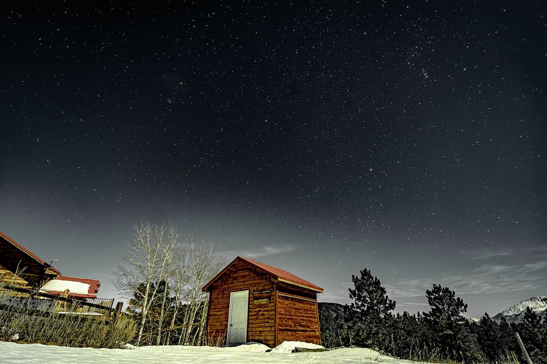 Red-roofed cabin in snow under a starry sky
