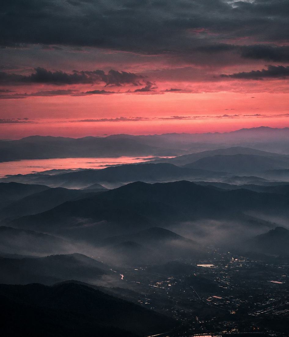 Layered mountain ridges in mist under a red sunset