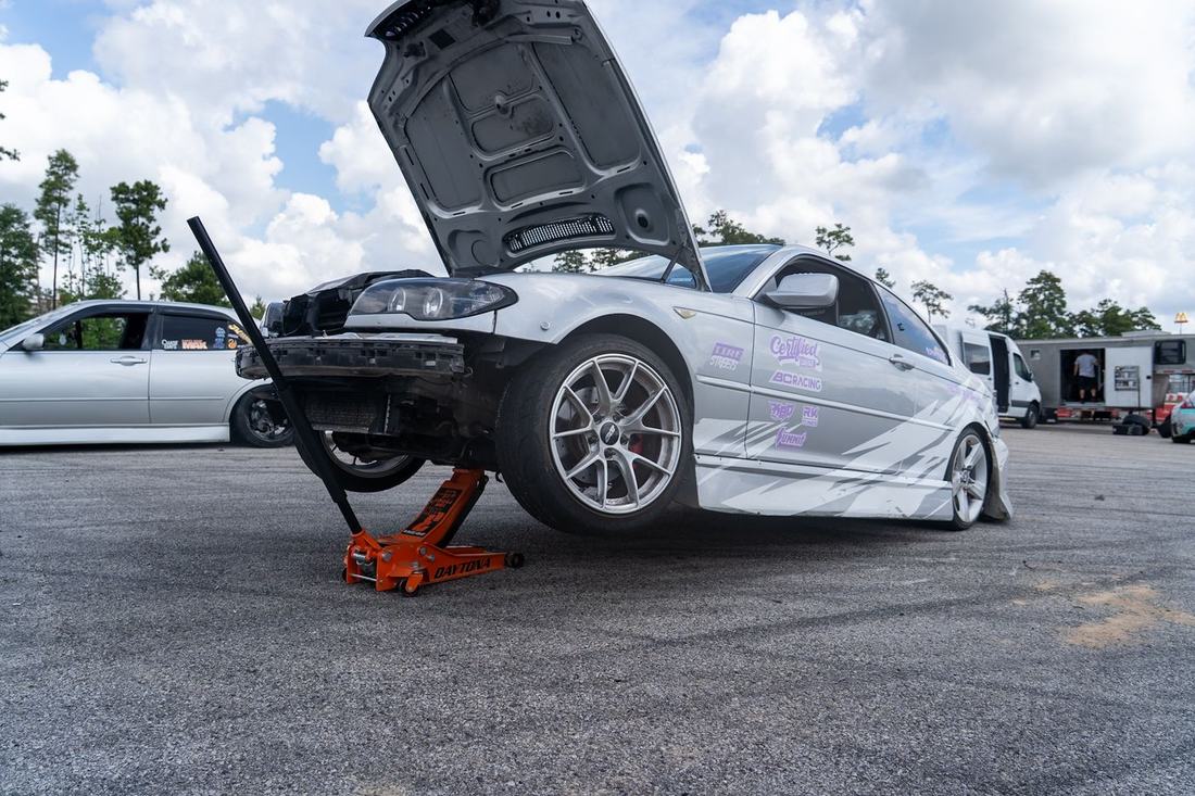 Drift car jacked up with its hood open in the pits