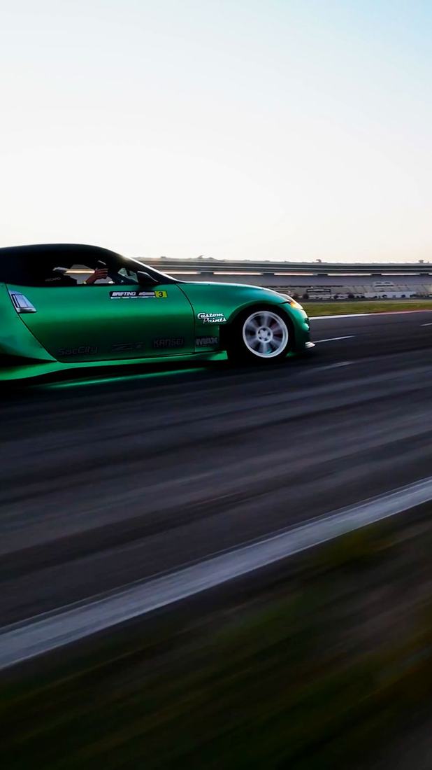 Low side chase shot of a green drift car
