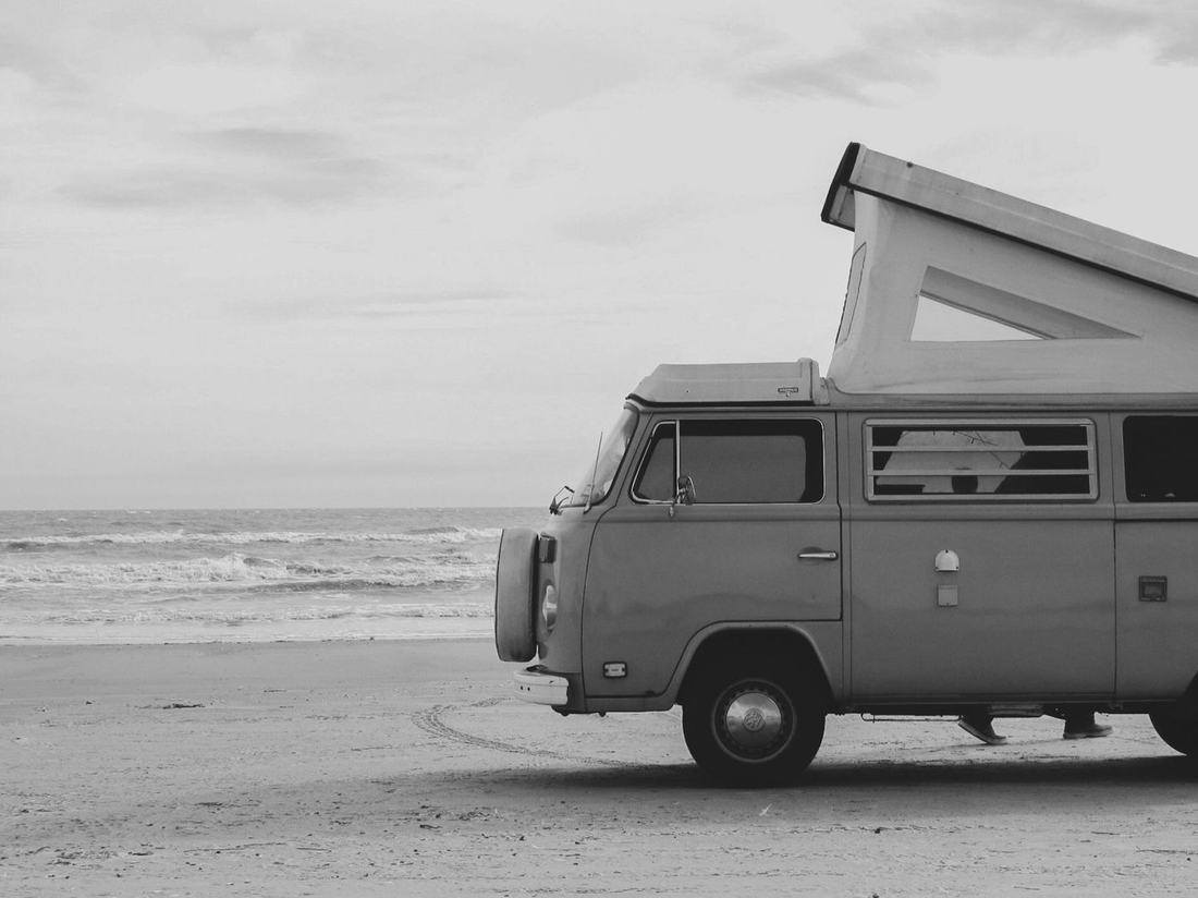 Black and white camper van parked on a beach