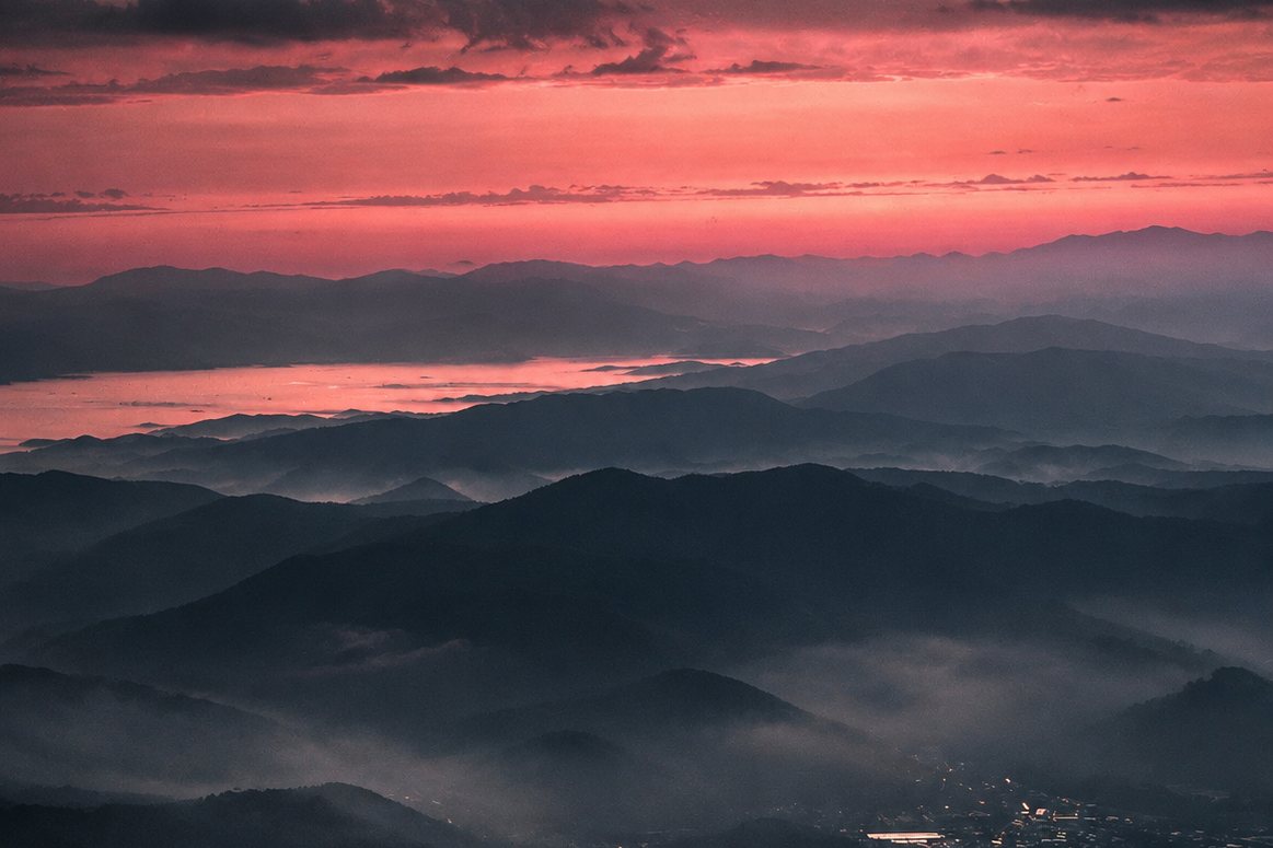 Layered mountain ridges in mist under a red sunset