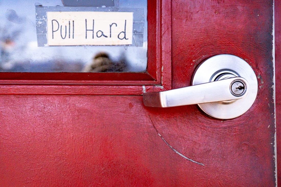 Red door with a handwritten Pull Hard sign